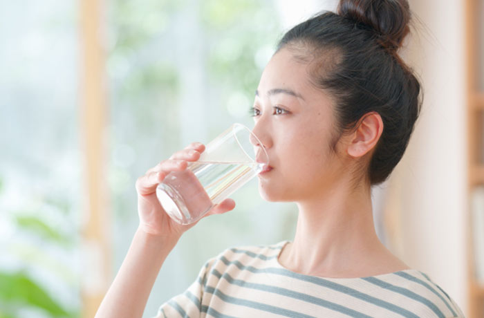 
夏の脱水や口腔乾燥を防ぐためこまめに水分補給する女性 
